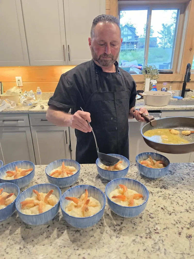 Chef Joe plating a long row of bowls for a private event