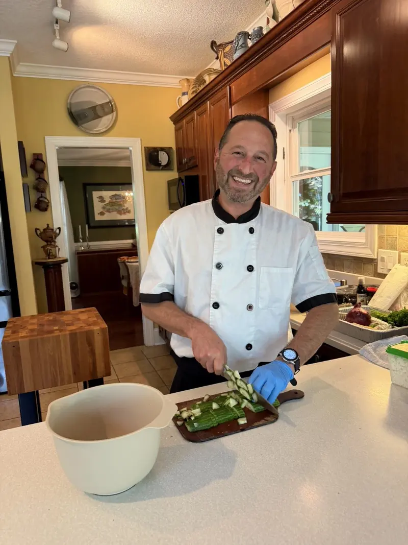 Chef Joe in his whites prepping vegetables on a cutting board in a home kitchen